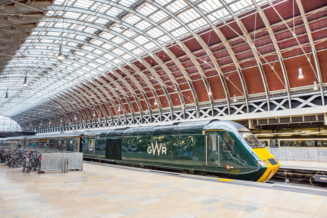 Great Western Railway train at station platform under Victorian arched roof.