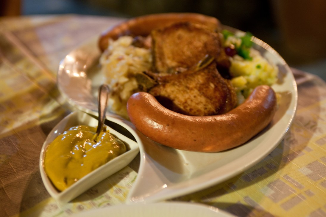 A plate of German sausage with bread, mustard and potato salad.