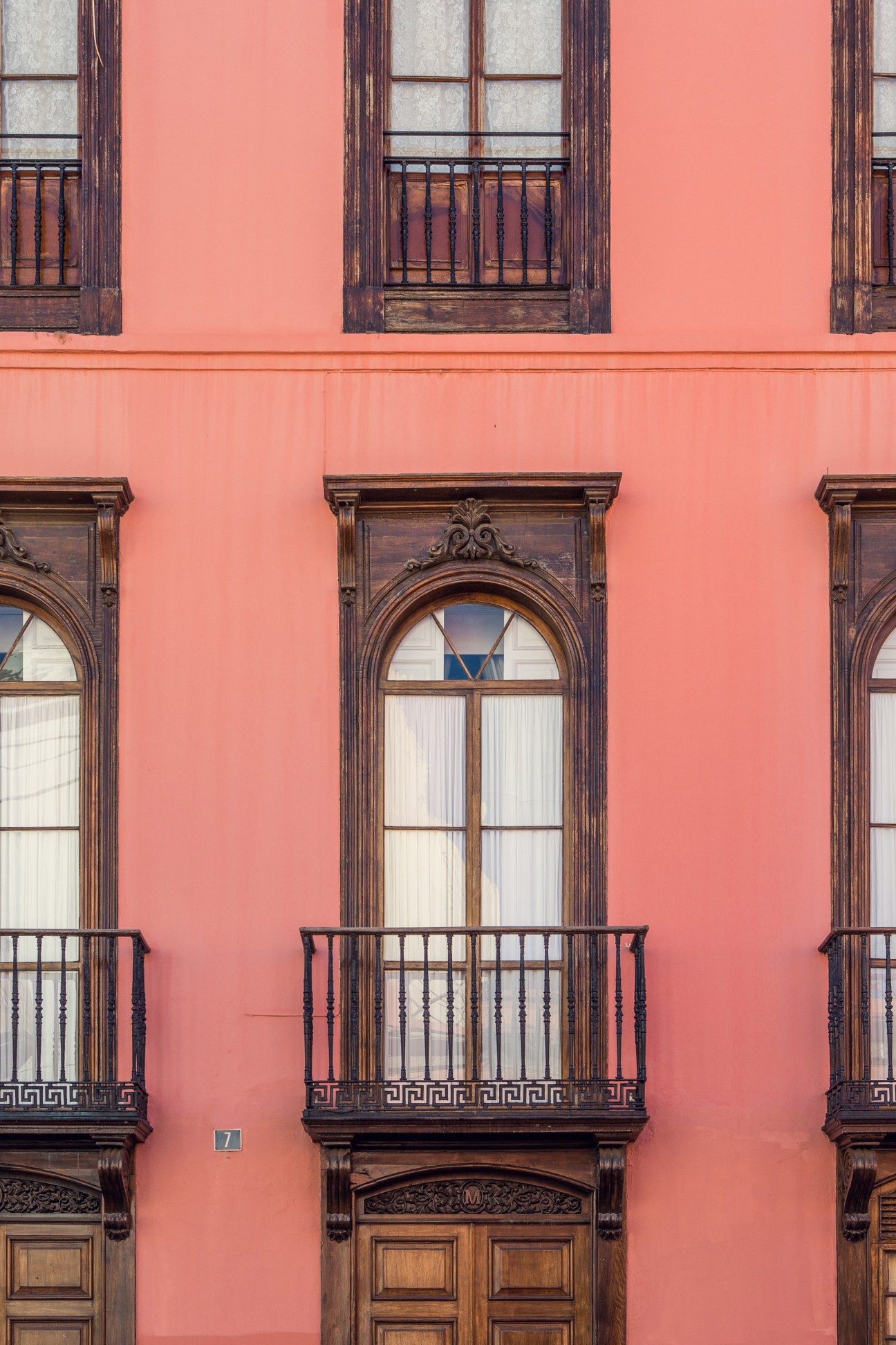Coral-pink colonial building with dark wooden balconies and ornate window frames in La Vegueta, Las Palmas.