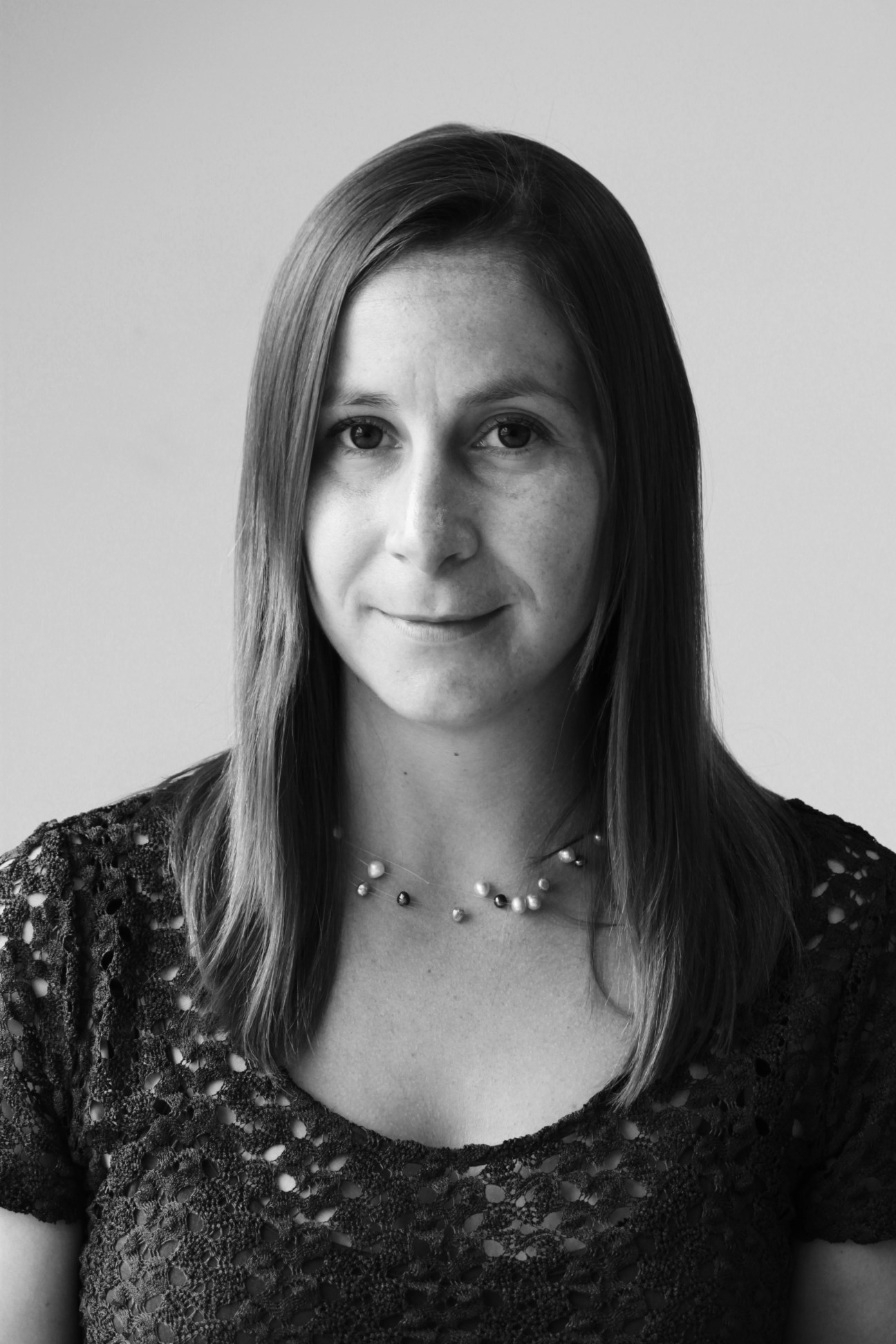 Black and white headshot portrait of a woman with long hair wearing a beaded top.