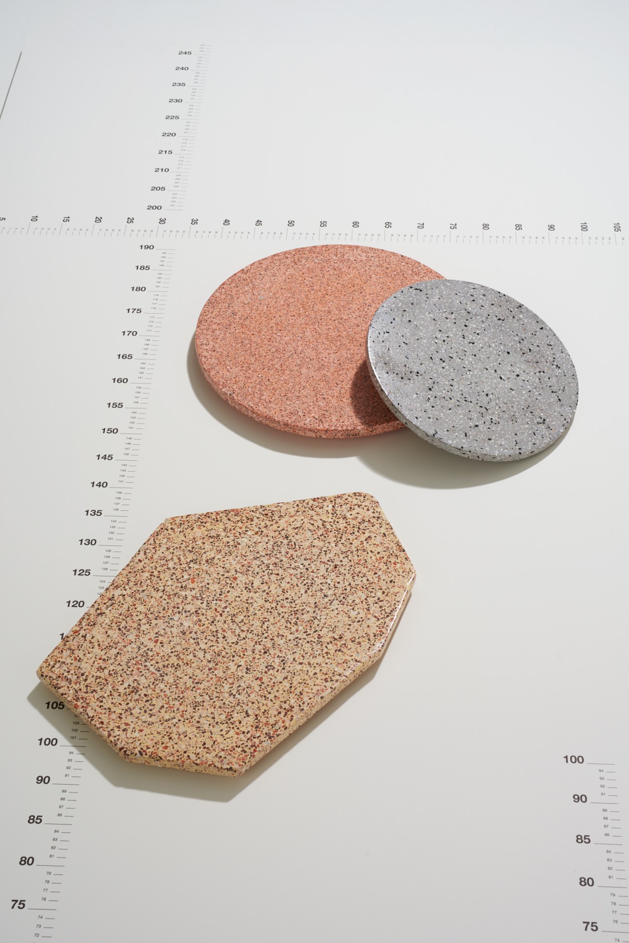 Three speckled terrazzo chopping boards in coral and gray tones displayed with a ruler for scale.