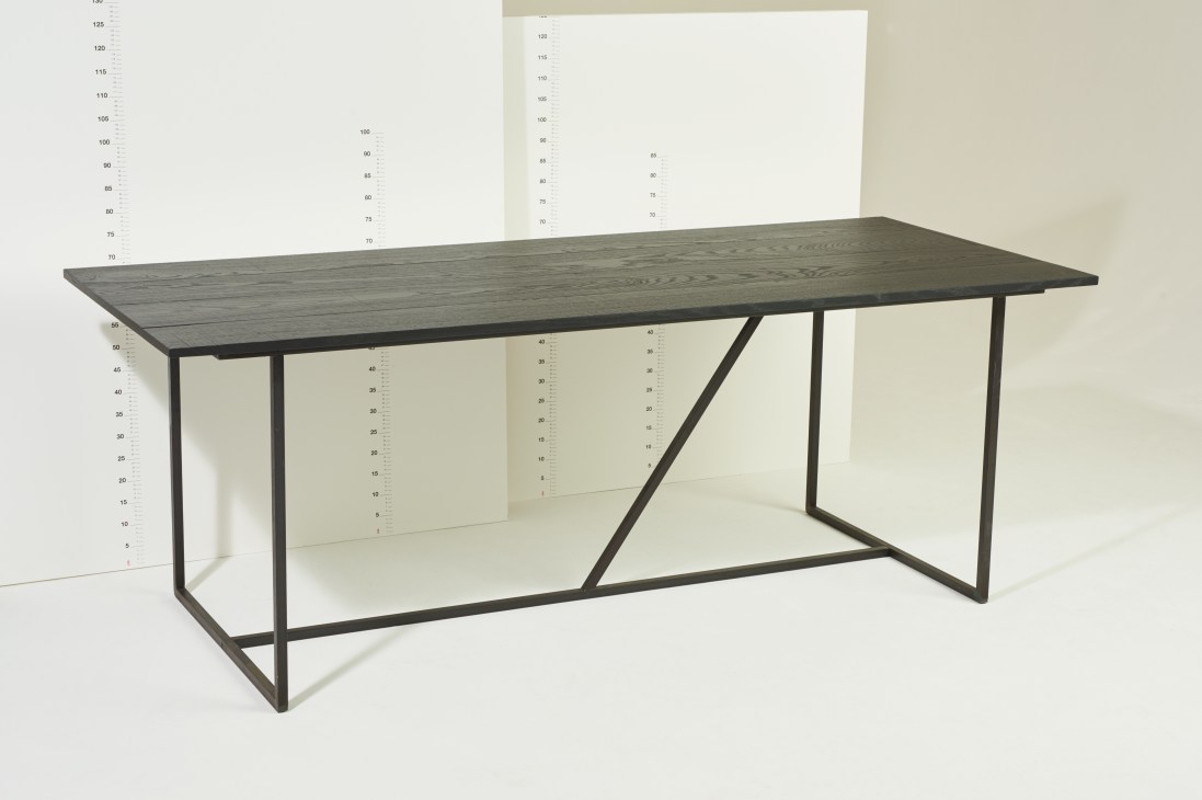 Mesa Nero table with dark oak top and diagonal steel bar support on coated steel frame.