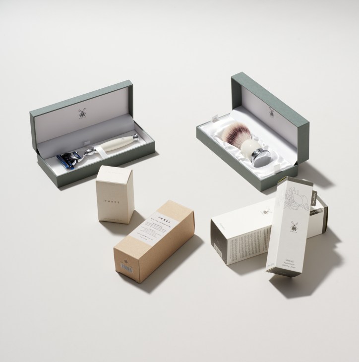 Three and Mühle skincare and shaving products displayed in open green boxes with white interior packaging.