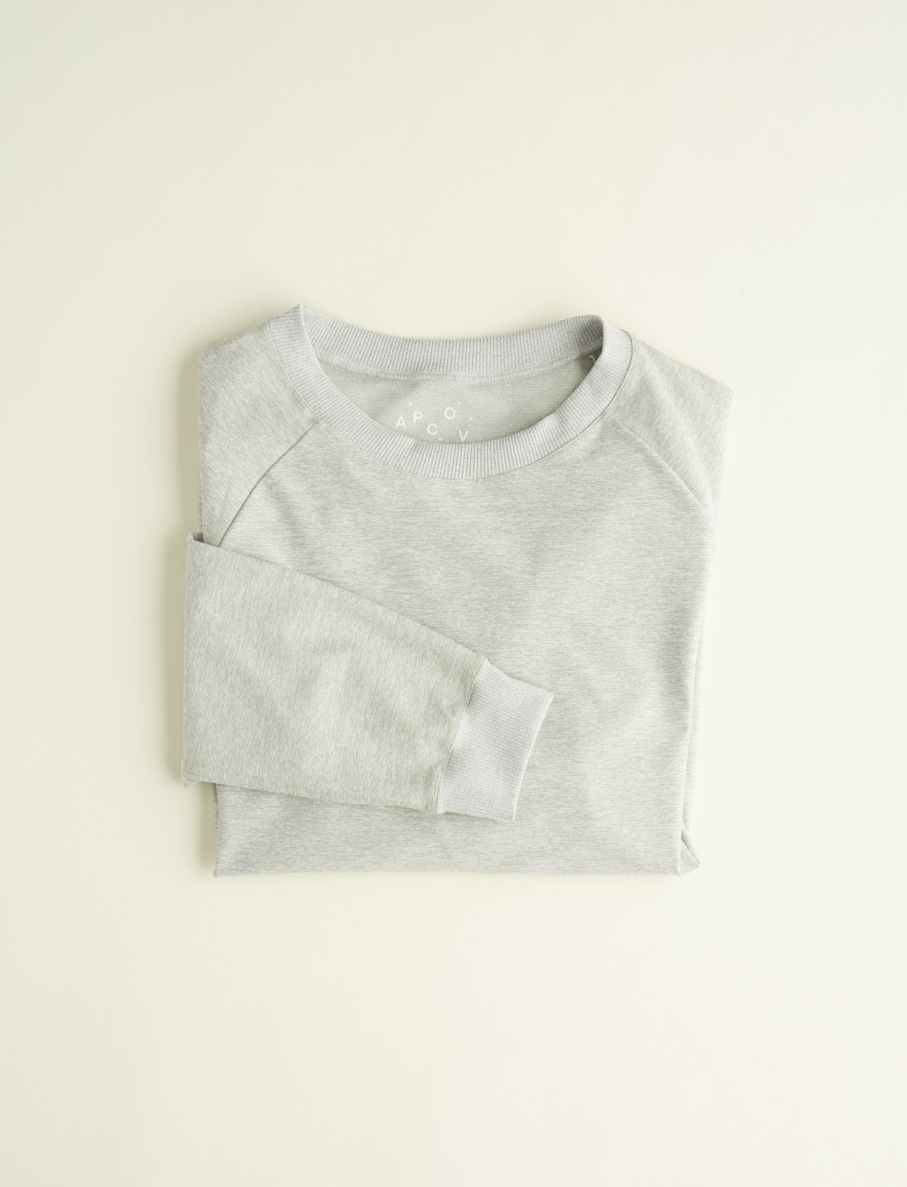 Folded cream-coloured sweatshirt with ribbed crew neck and cuffs on neutral background.
