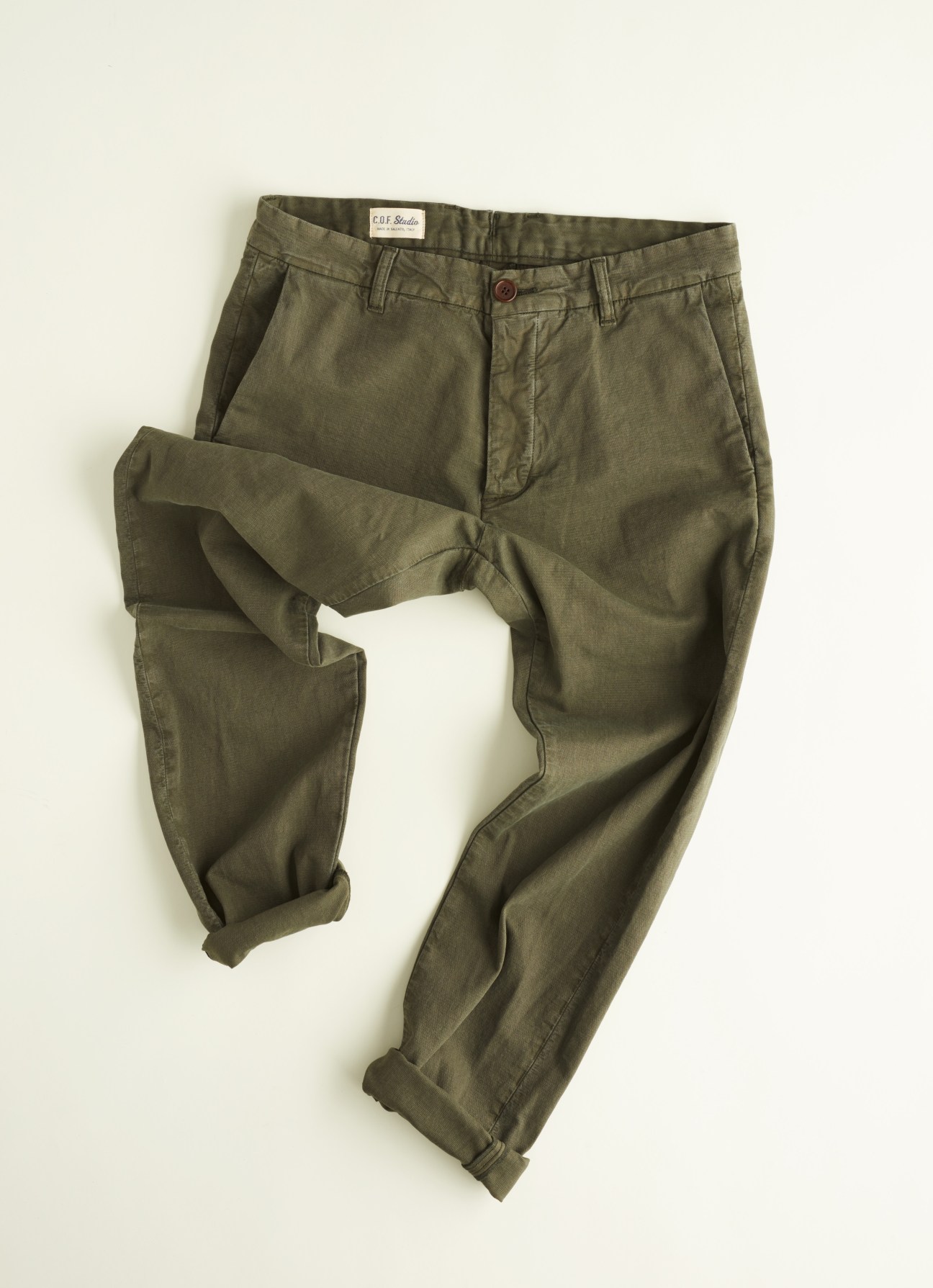 COF Studio olive chinos in French-milled cotton with rolled cuffs against a cream background.