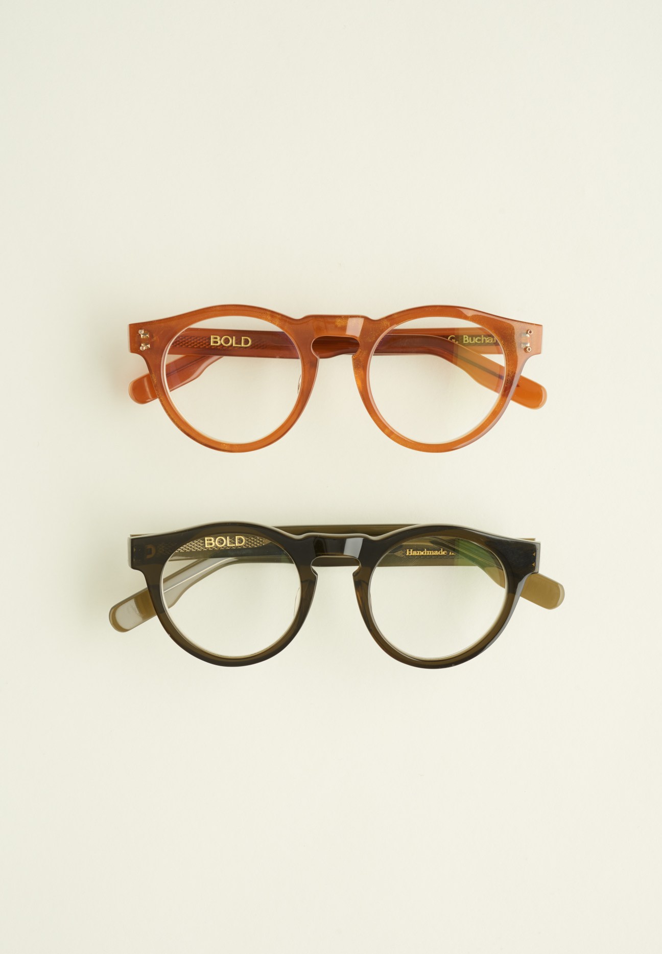 Two Bold eyeglasses in amber and olive acetate shades displayed against a neutral background.