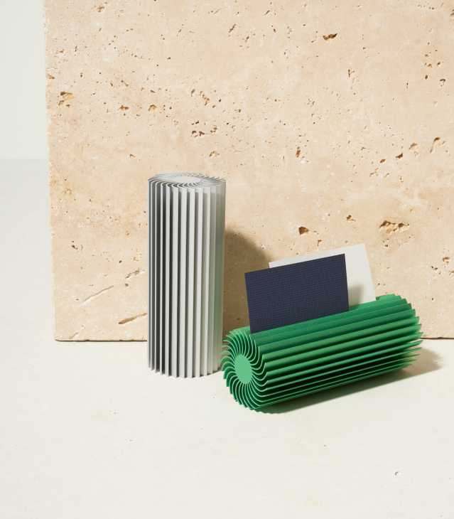 Hay card holder by Kutarq Studio with curved aluminium fins in grey and green, holding a dark business card.