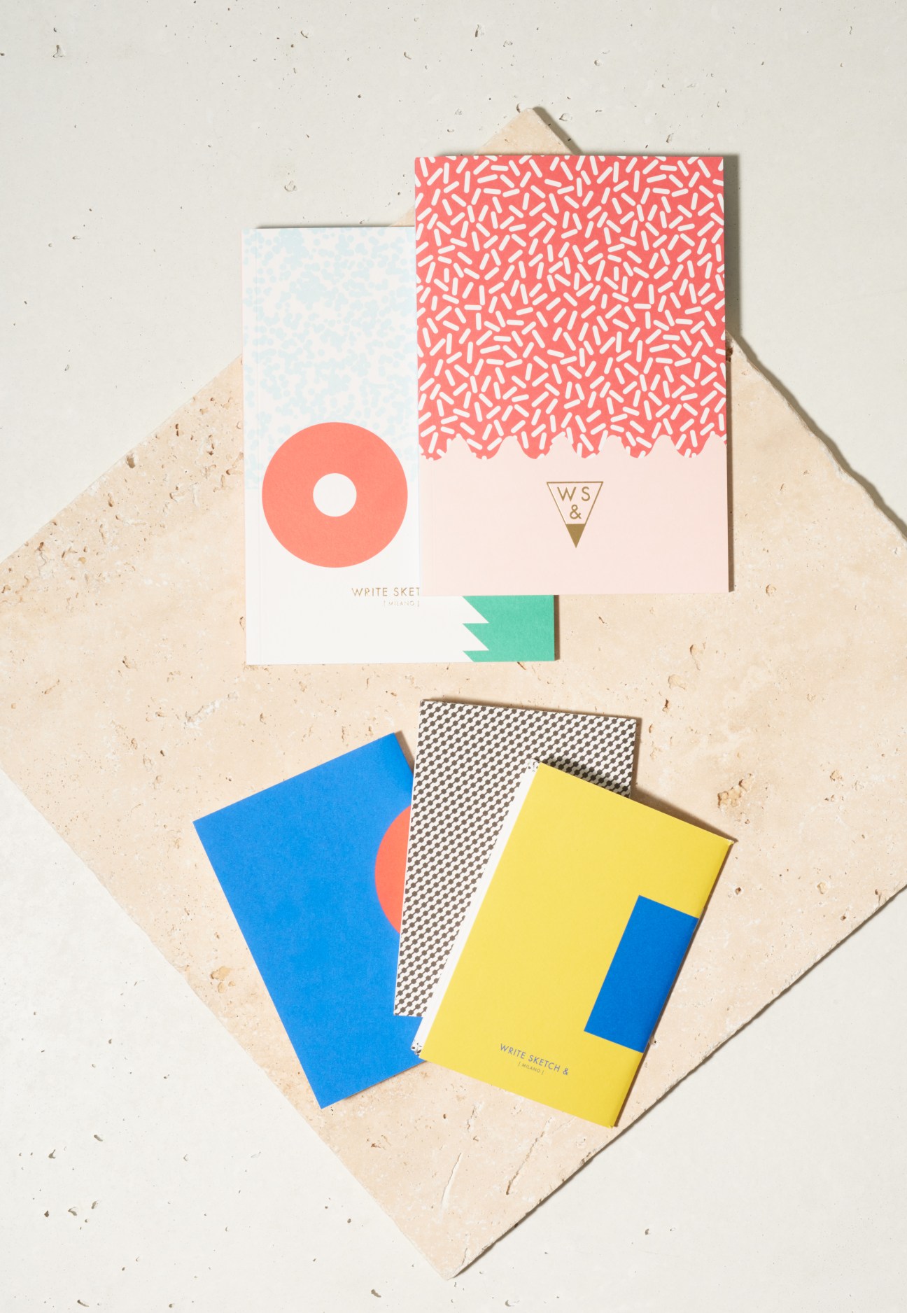 Write Sketch And notebooks displayed on a textured surface, featuring colorful Memphis Milano-inspired designs with geometric patterns.