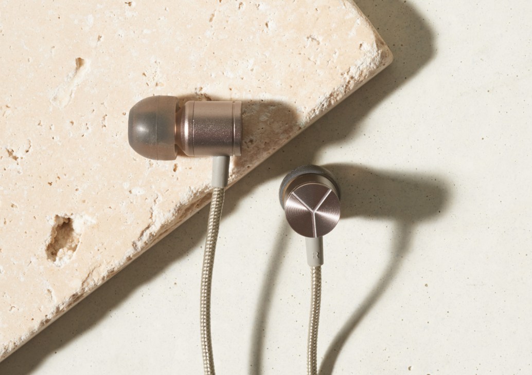 Ynoir copper earphones with single-piece design and beryllium ear buds on textured surface.