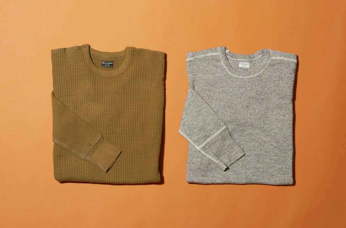 Two folded sweaters on orange background - olive waffle-knit and grey heathered crewneck