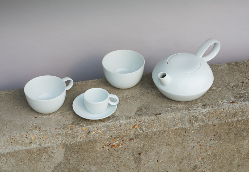 White ceramic tea set by Stefan Diez for Kawazoe Seizan with teapot, cups, bowl and saucer on concrete surface