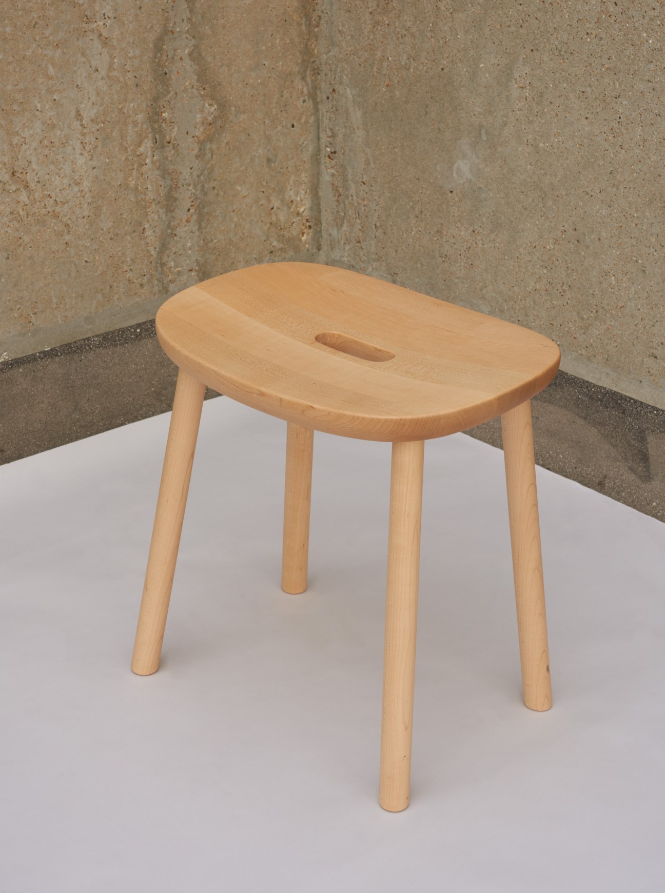 Wooden stool with oval seat featuring small handle cutout and four tapered legs