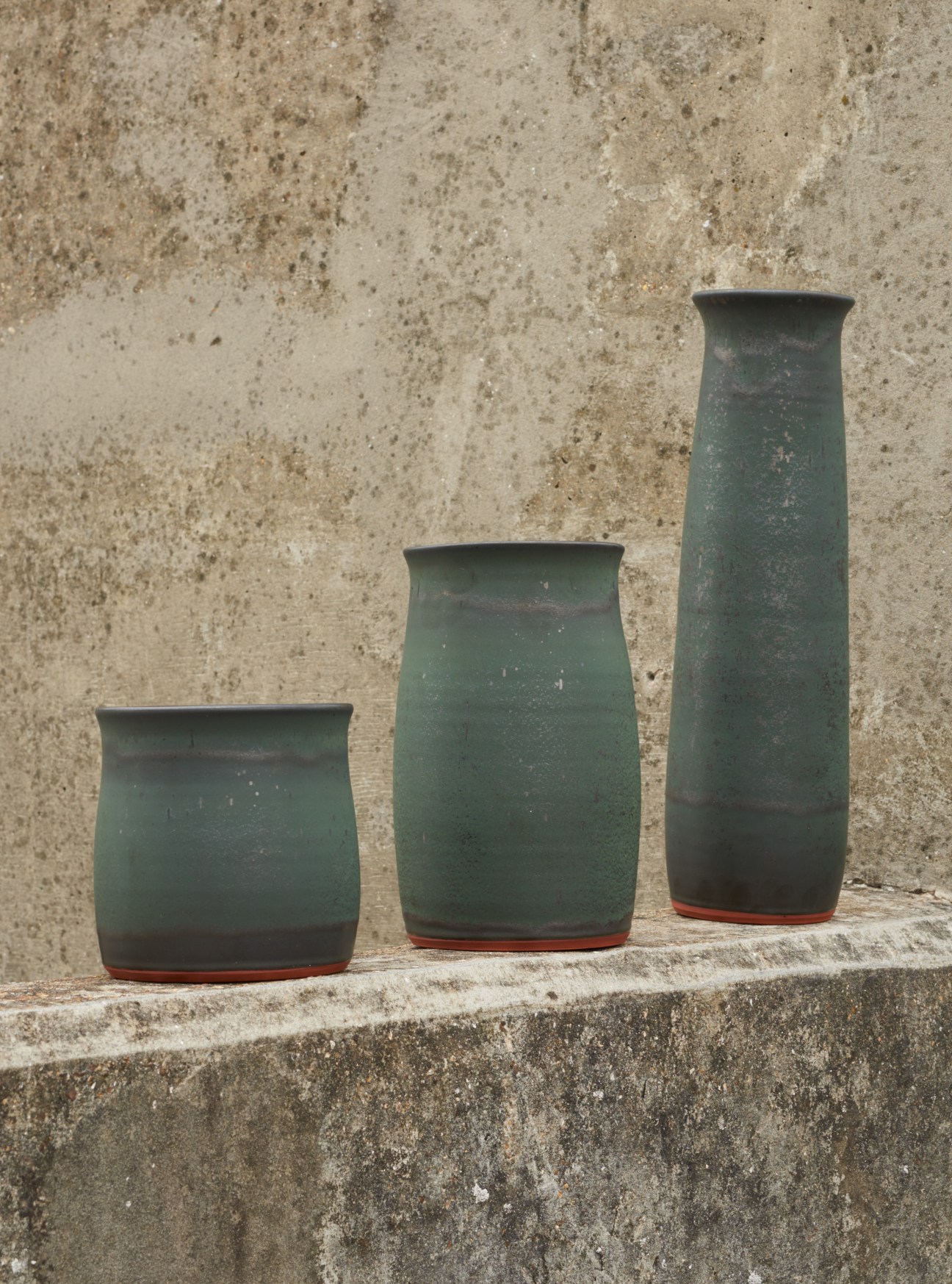 Three green terracotta vessels by Reiko Kaneko in graduated heights with glazed finish