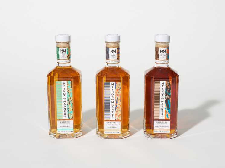 Three bottles of Method and Madness Irish whiskey with colorful labels displayed against a white background.