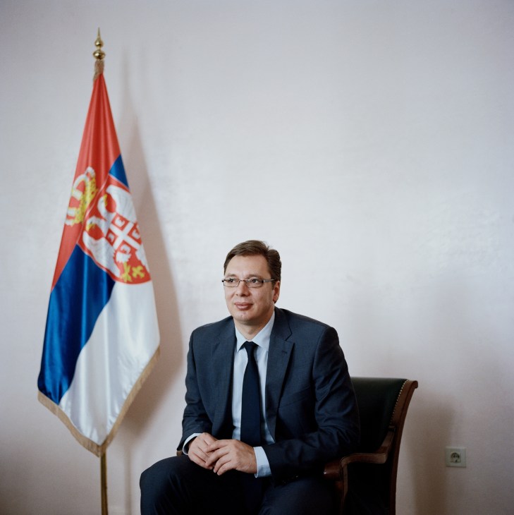 Aleksandar Vucic, Serbia's first deputy prime minister, seated in front of the Serbian flag.