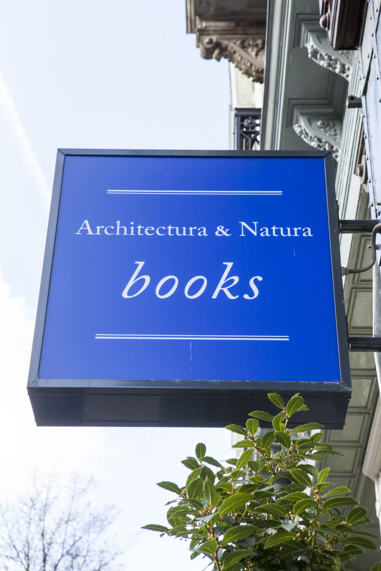 Blue storefront sign for Architectura & Natura bookshop in Amsterdam with white text