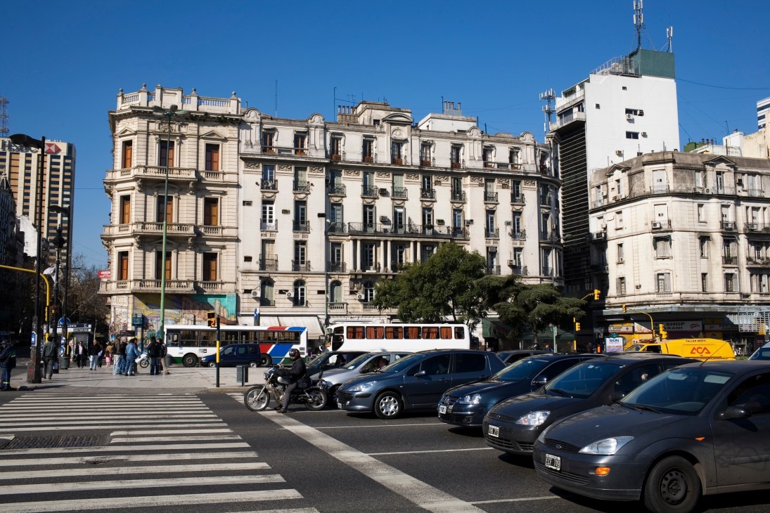Montserrat street scene with elegant 19th-century French-influenced buildings, parked cars, and public transport in Buenos Aires.