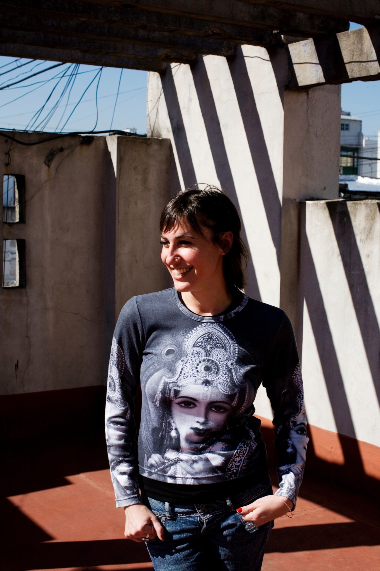 Woman standing on a rooftop terrace with geometric shadows cast by overhead structures in Buenos Aires.