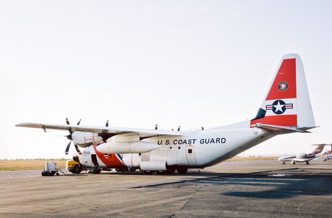 U.S. Coast Guard Lockheed Martin HC-130J propeller plane parked on tarmac.