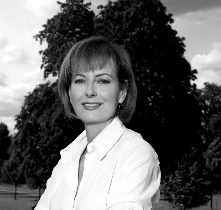 Black and white portrait photograph of a woman with short dark hair and a gentle smile, wearing a light-colored top.