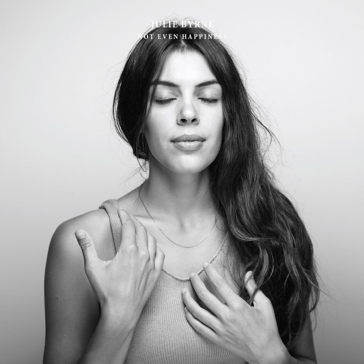 Black and white portrait of Julie Byrne with long dark hair and eyes closed, with text overlay reading 'JULIE BYRNE NOT EVEN HAPPINESS'