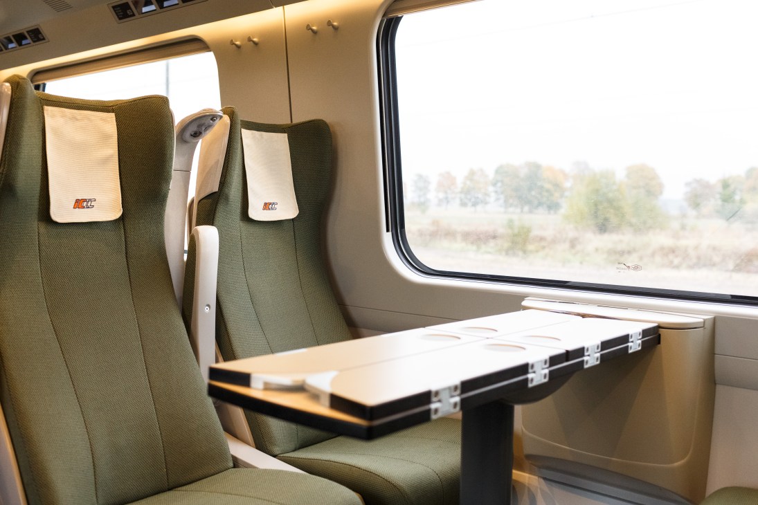 ÖBB Railjet business class interior with reclining seats, table, and window view of landscape.