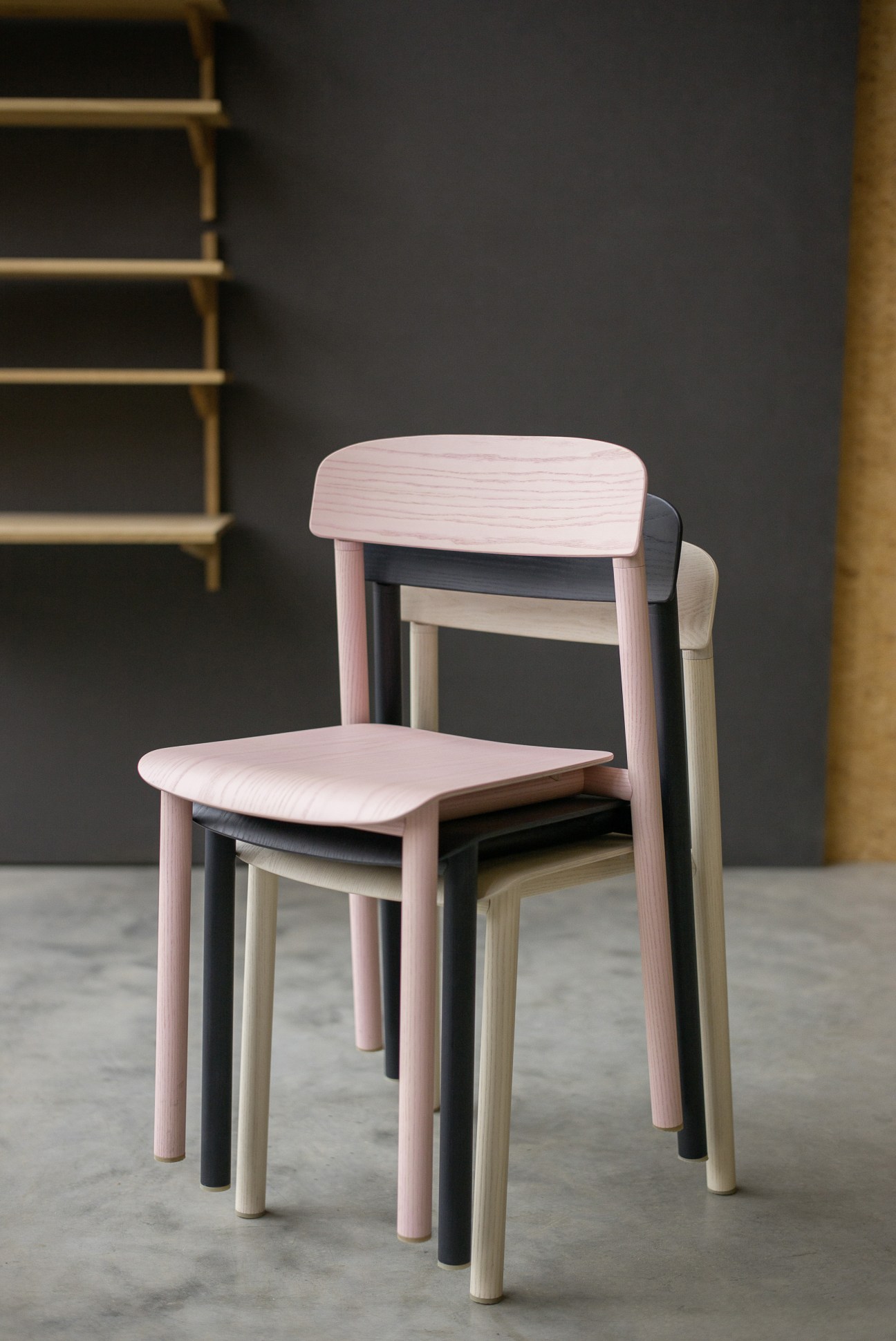 Stattmann Neue Moebel wooden chairs in pink, black and natural finishes stacked together.