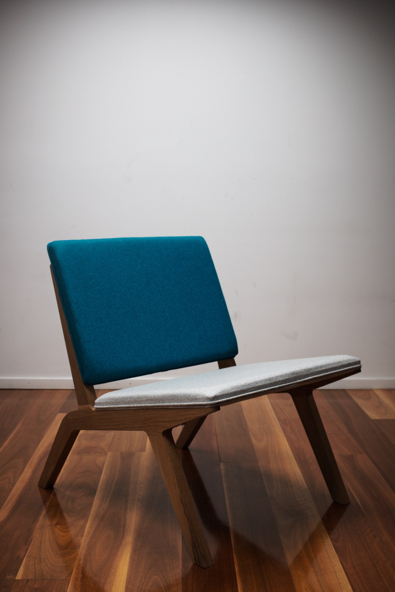 Nomi Woodstack chair in solid timber with teal upholstered backrest and gray seat cushion.