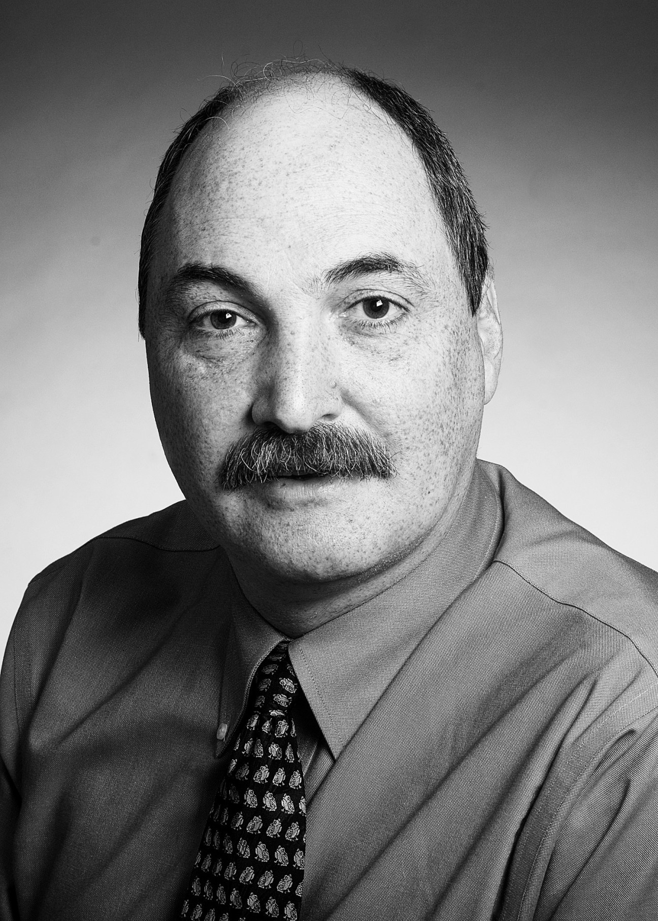 Black and white portrait photograph of James Lewis, a man with a mustache wearing a shirt and patterned tie.