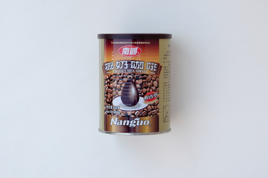 Nanguo brand ground coconut-milk coffee powder in a cylindrical tin container with Chinese and English labeling.