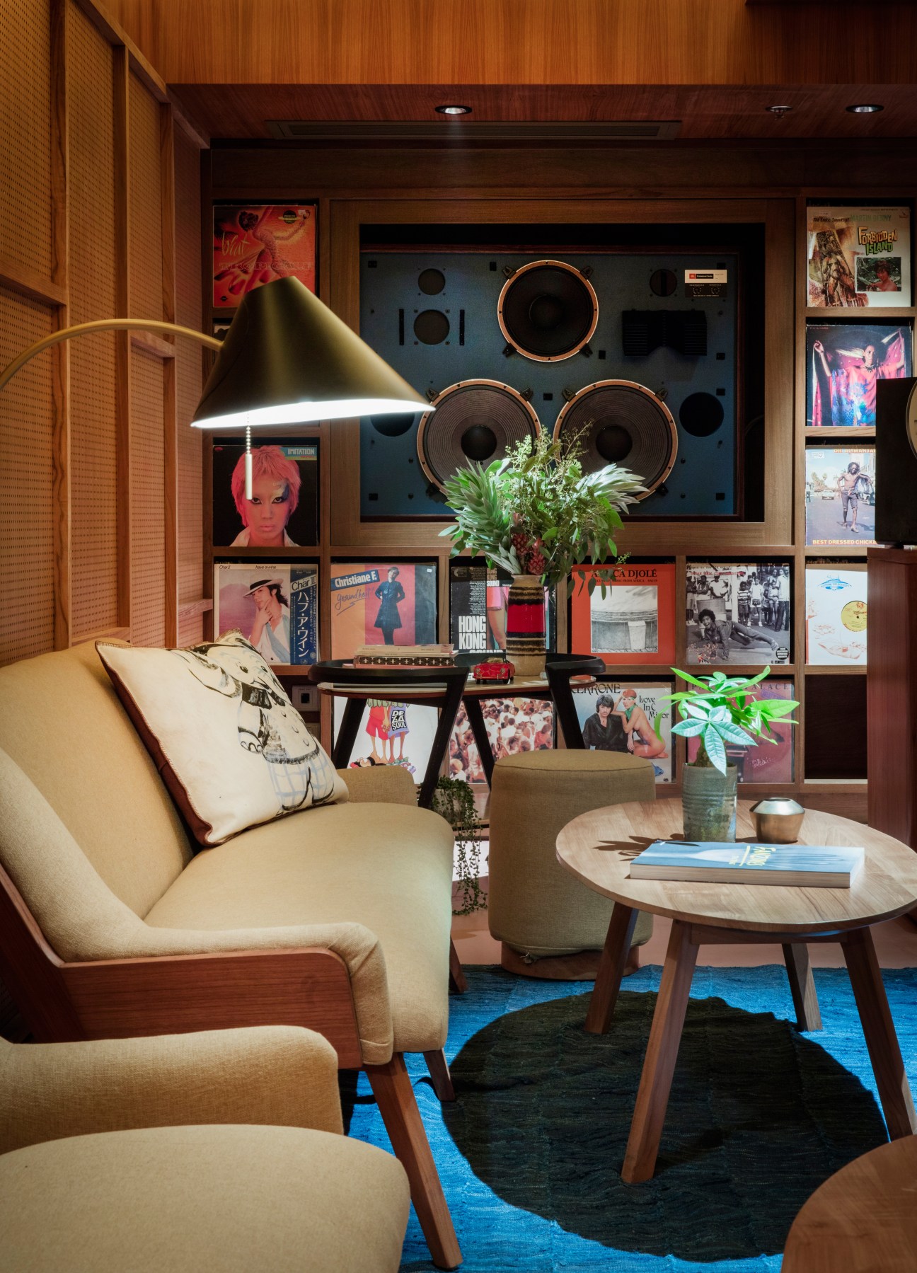 Mid-century modern listening room with built-in speakers, vinyl records, and warm wood paneling