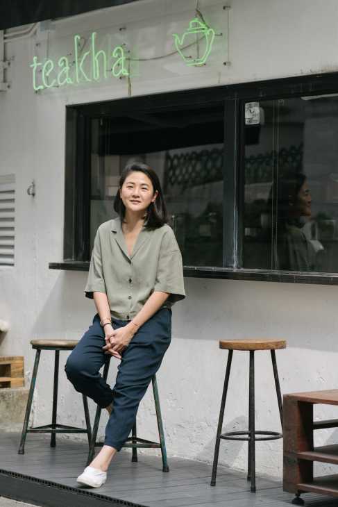 Nana Chan, founder of Teakha teahouse, sitting outside her Hong Kong establishment with green neon signage.