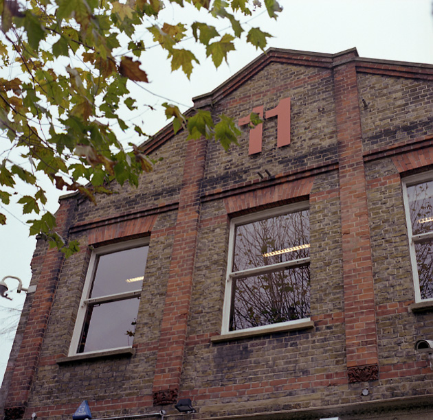 Red brick building with large windows and ivy, former milk factory housing Pentagram design agency in London.