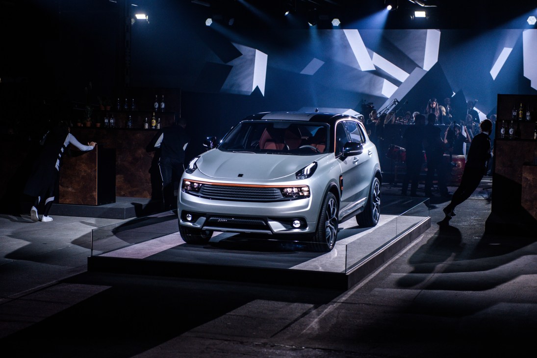 White Lynk & Co 01 SUV on display stage at Berlin launch event with audience and dramatic blue lighting.