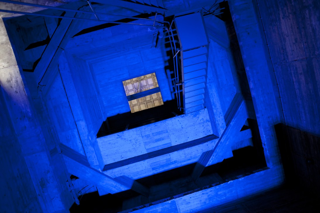 Interior view of St Agnes church in Berlin during renovation, illuminated in blue light with brutalist architecture visible.