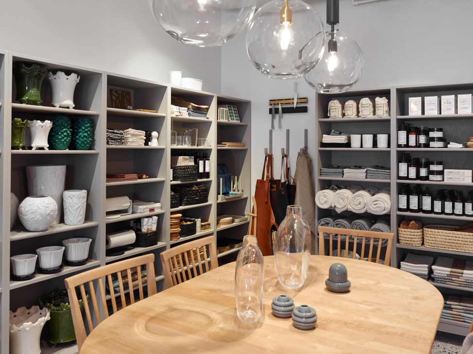 Interior of Malmstenbutiken Stockholm showroom with white shelving displaying home goods and glass pendant lights