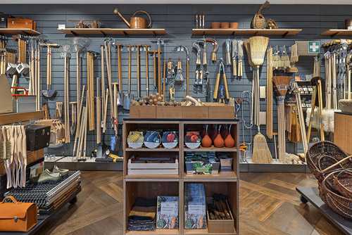 Organized tool display wall at Manufactum Vienna shop featuring hand tools, garden implements, and storage baskets.
