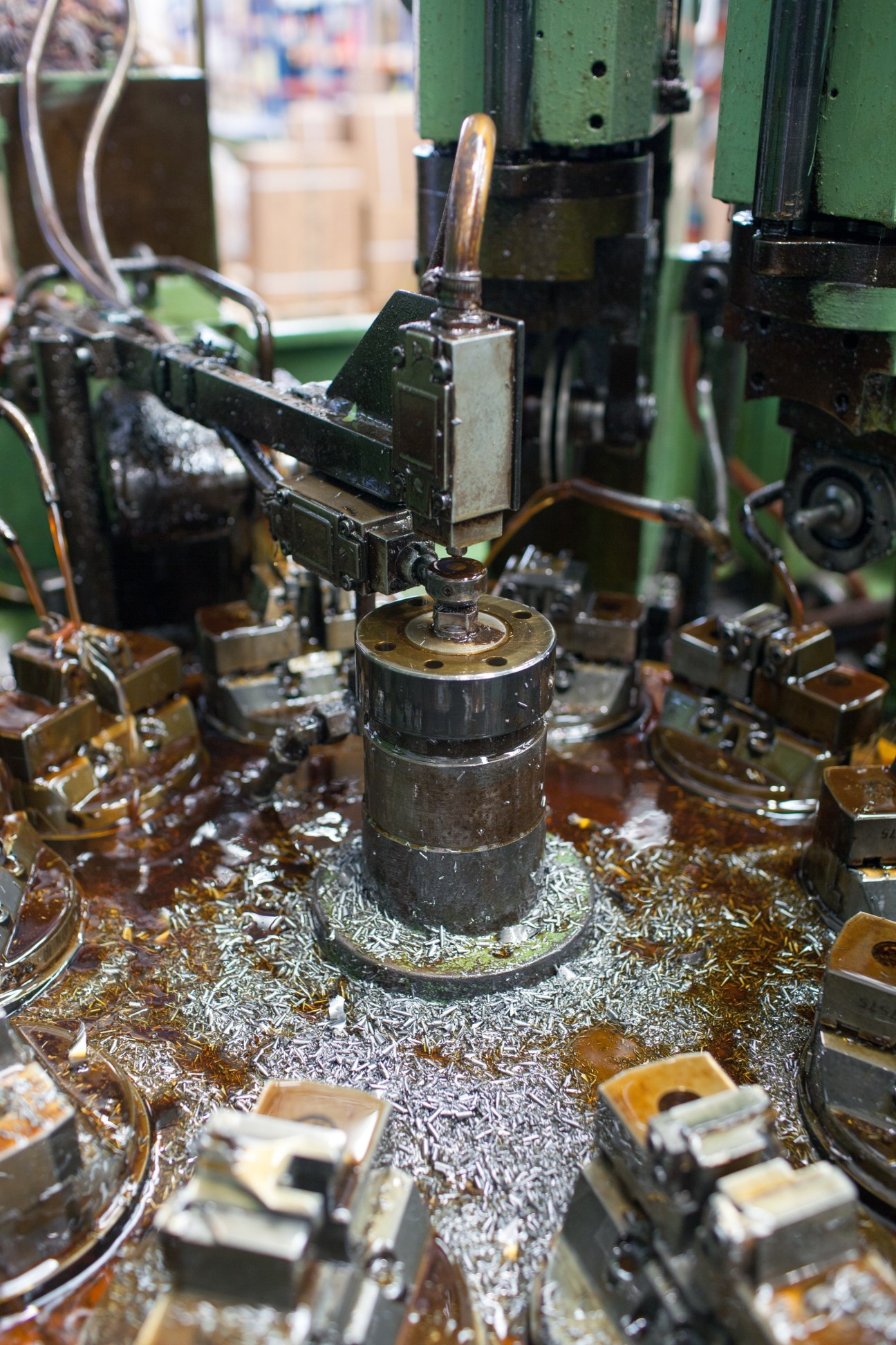 Industrial metal cutting machine with precision drill and metal shavings at El Casco factory.