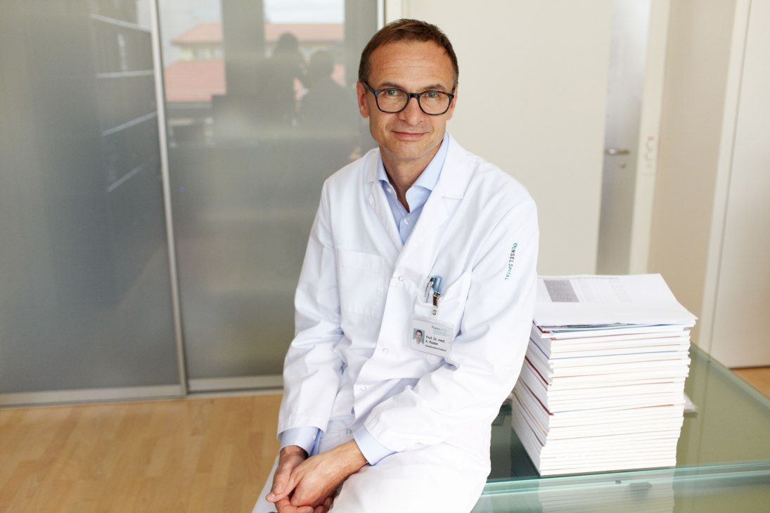 Prof Dr Andreas Raabe, head of neurosurgery at Bern's Inselspital hospital, in his office with a stack of medical files.