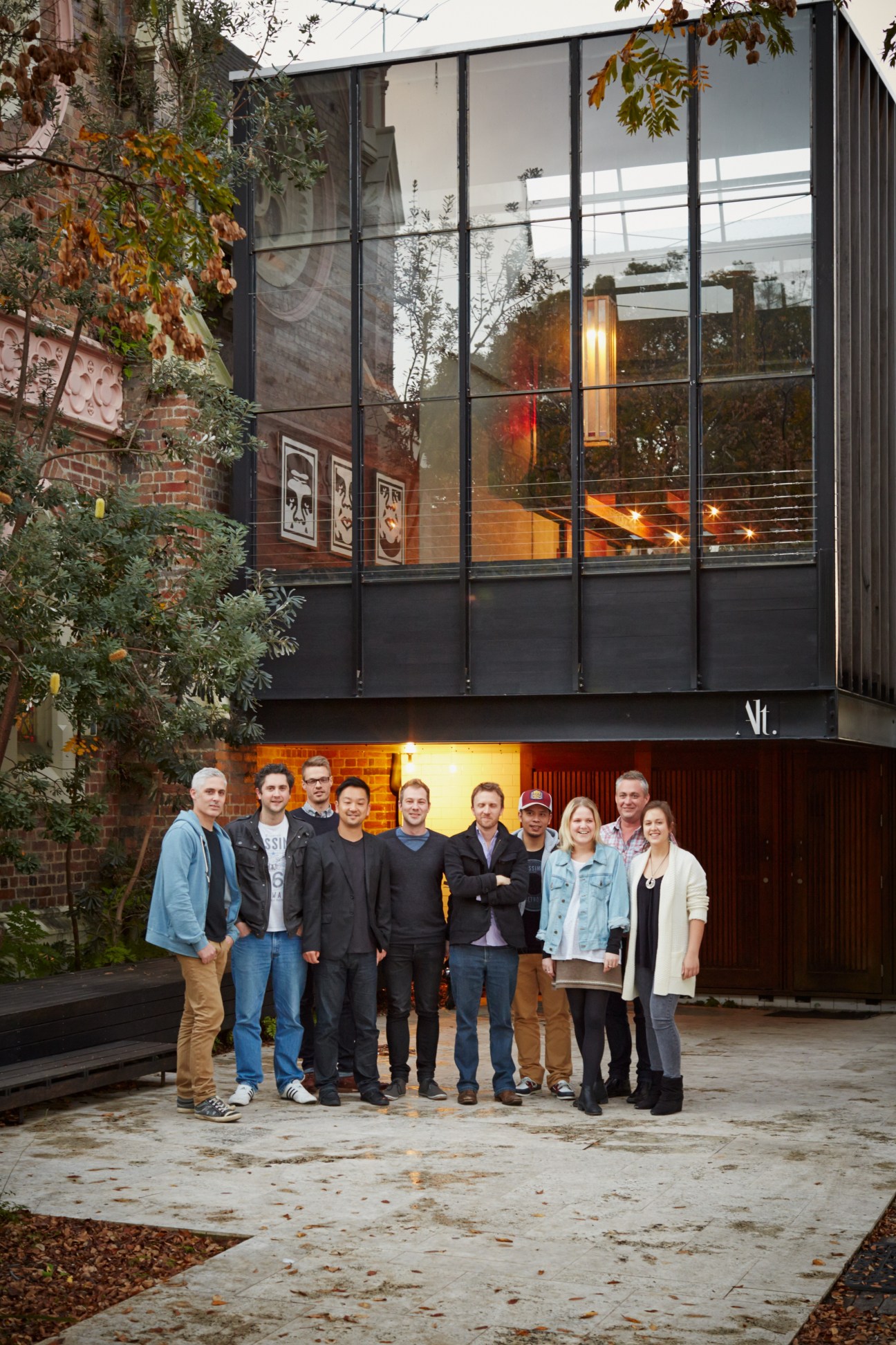 Team of approximately 10 people posing outside a modern building with large windows at Fuzzco headquarters