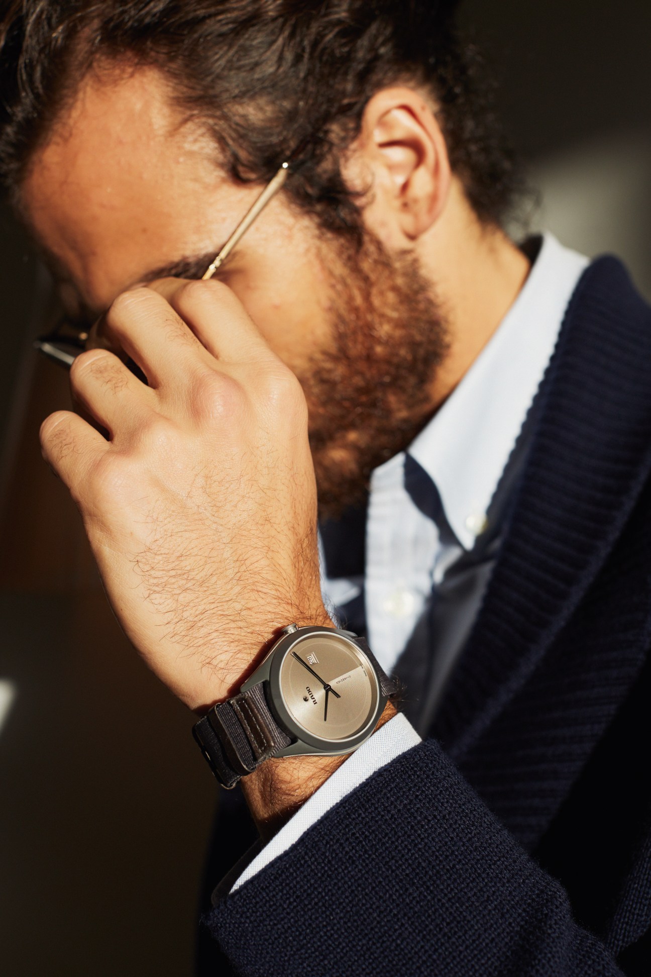 Man wearing Dunhill jacket and shirt with Persol glasses and Rado watch, smoking a cigarette.