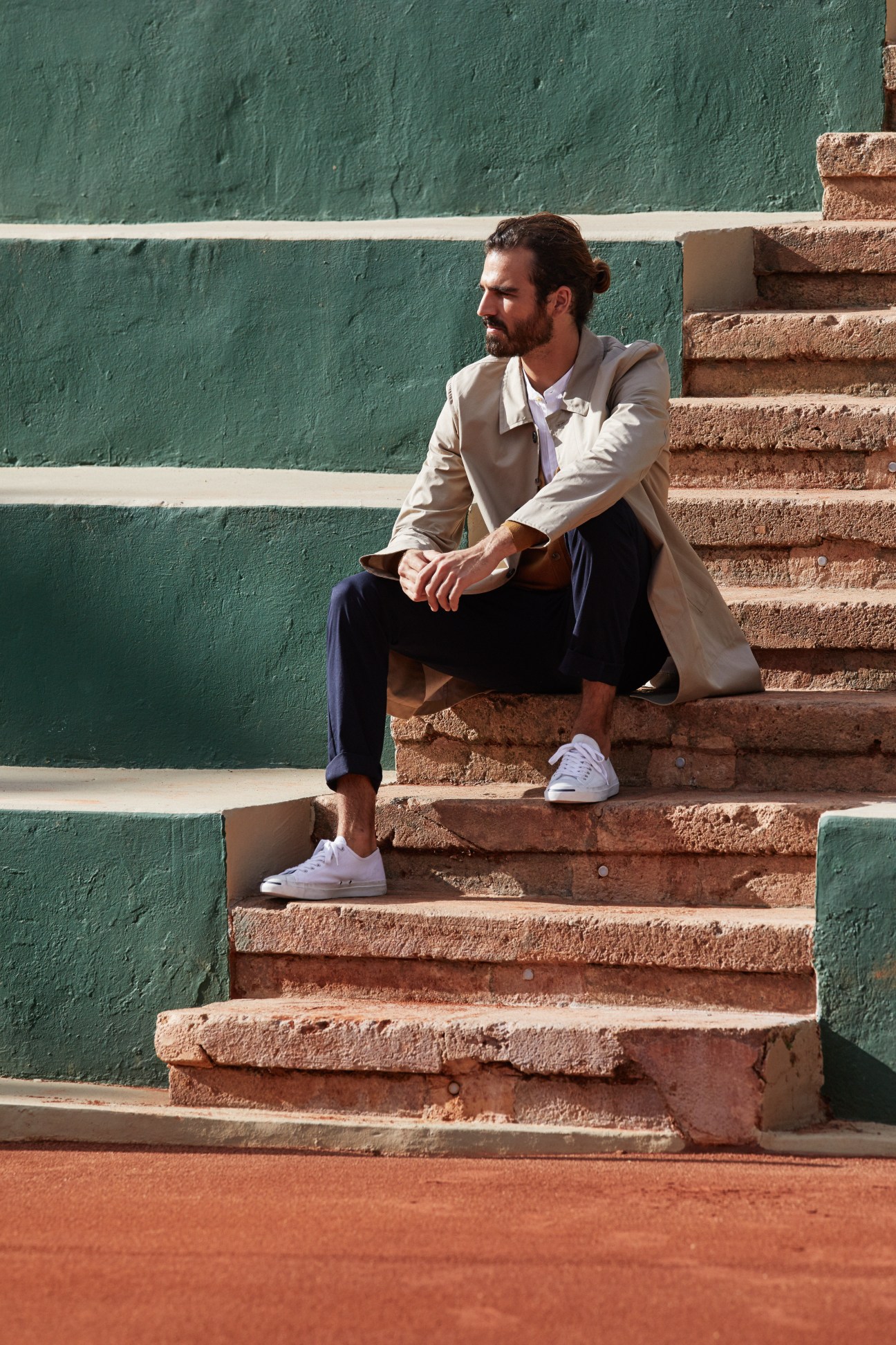 Man sitting on clay tennis court steps wearing President's coat, Closed cardigan, Oliver Spencer shirt, Woolrich trousers and Converse trainers.