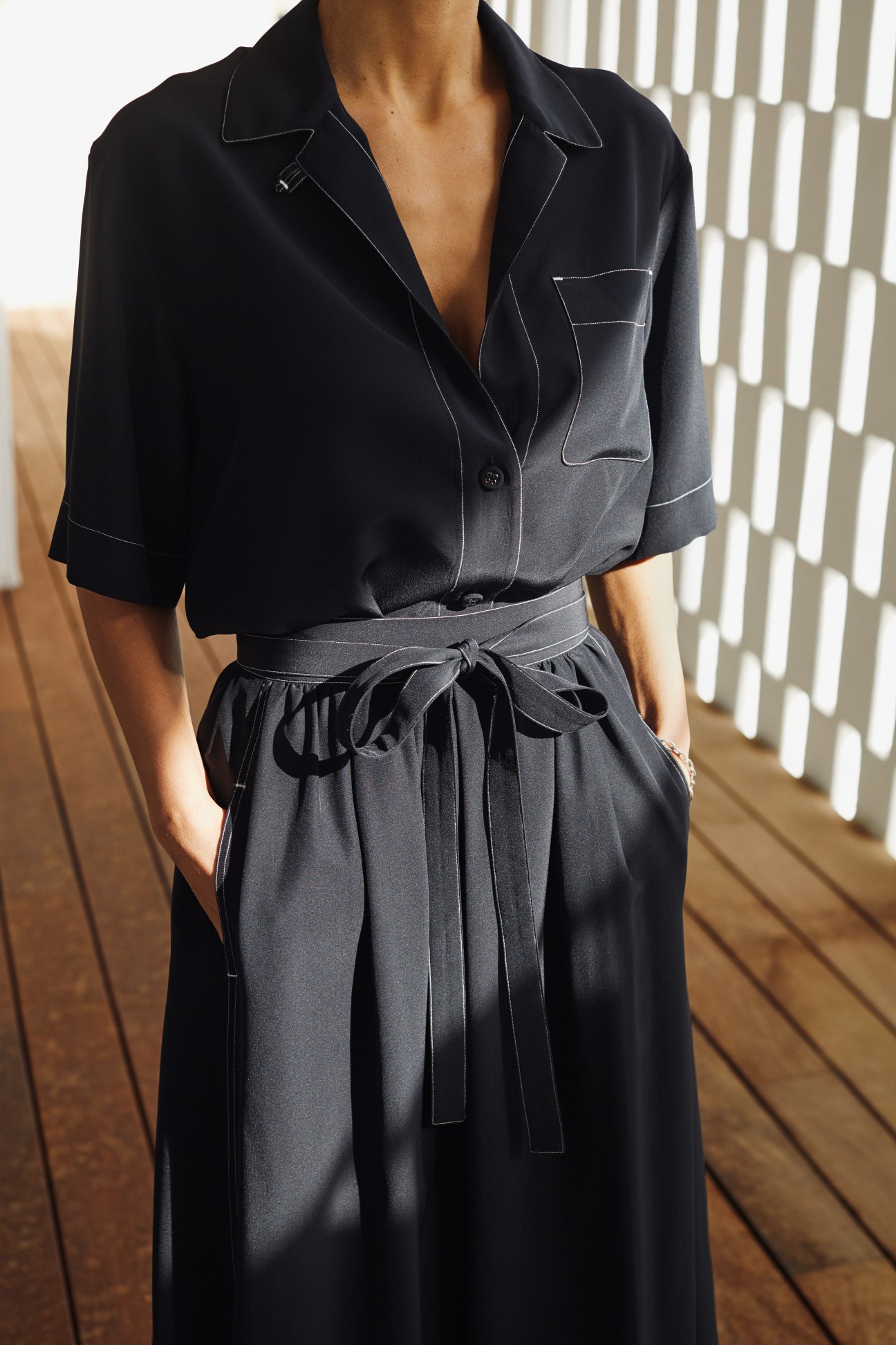 Woman wearing a Bottega Veneta shirt and skirt with a Saskia Diez bracelet.