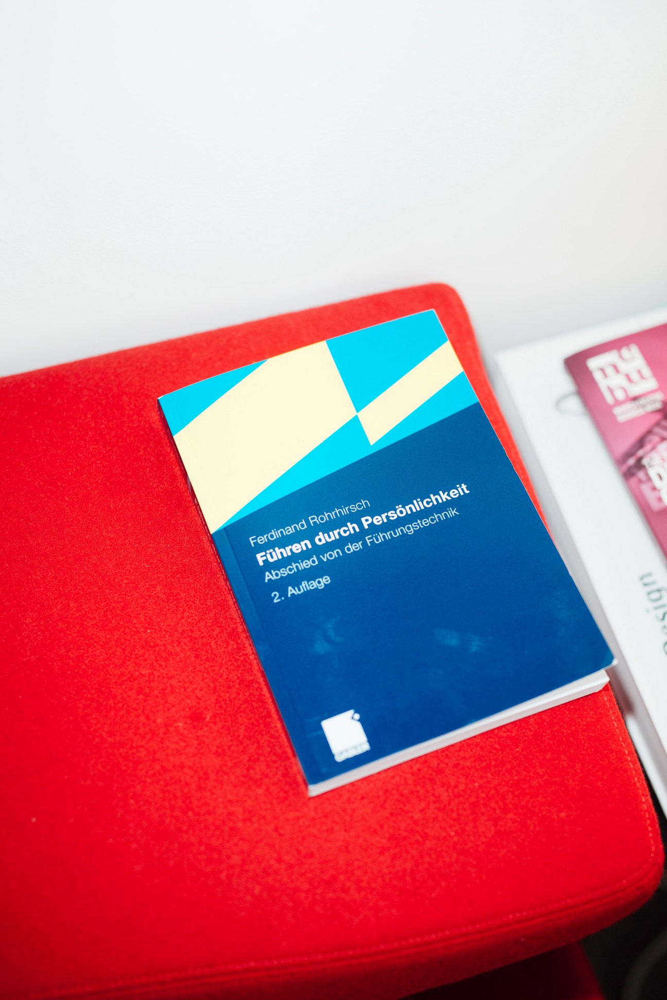 Ferdinand Rohrhirsch's book "Führen durch Persönlichkeit" (Leadership Through Personality) on a red surface.