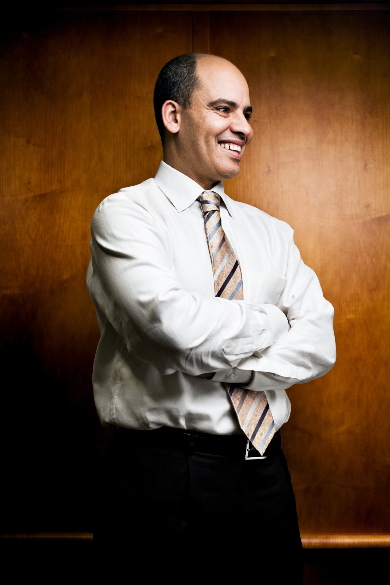 Portrait of Abderrahim Foukara, Al Jazeera bureau chief, in white shirt and striped tie against brown background.
