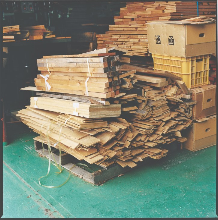 Stacked wooden planks and cut pieces in Mastro Geppetto's workshop with yellow storage crates.