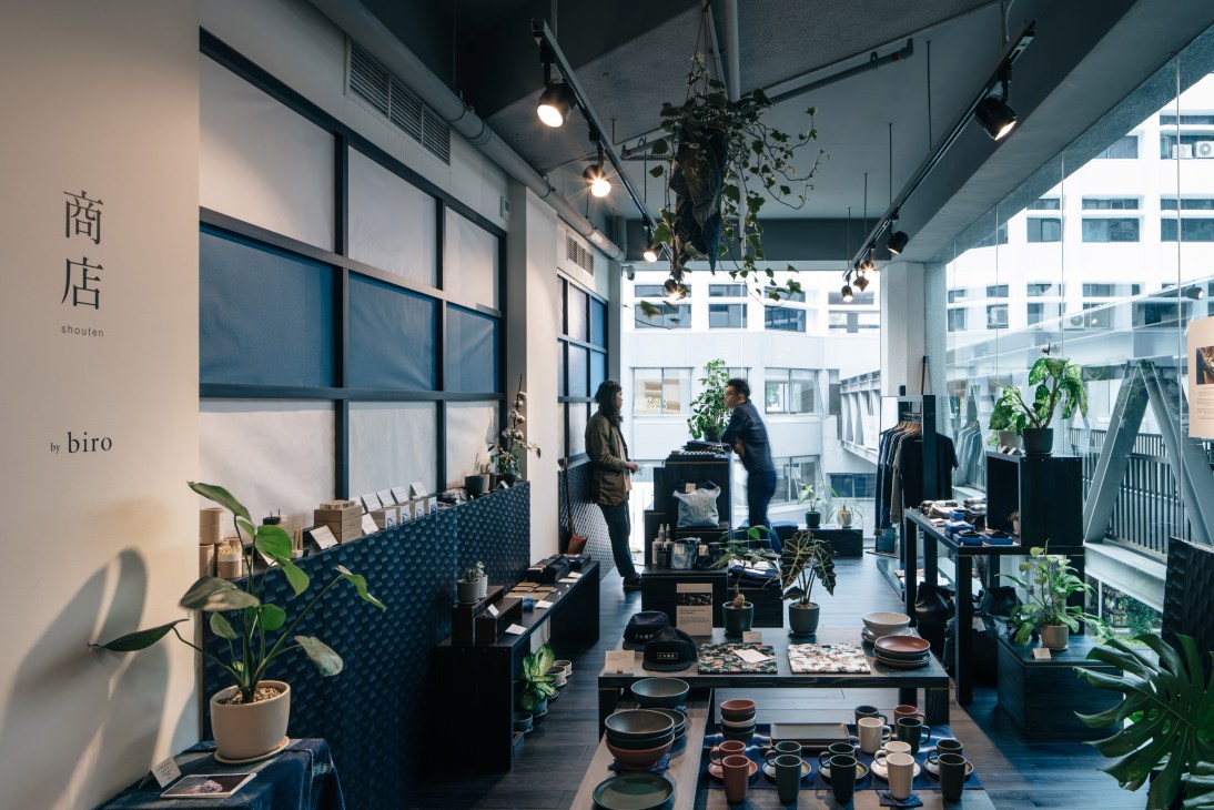 Interior of Biro shop in Singapore featuring ceramic bowls, clothing displays, and hanging plants under track lighting.