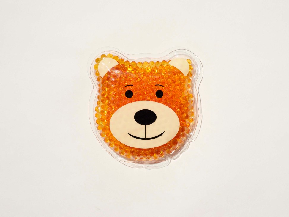 Orange bear-shaped cooling gel mask with cute face design and clear plastic packaging.