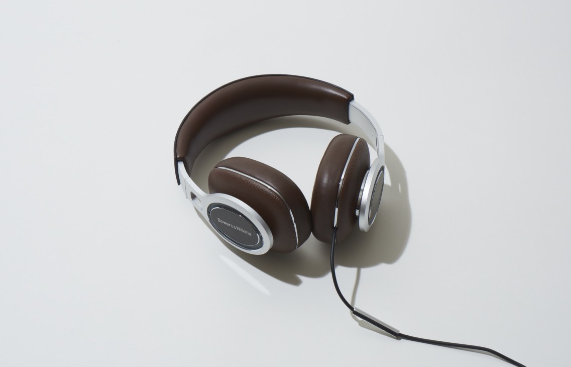 Bowers & Wilkins over-ear headphones with brown ear cups, white headband, and black cable on white background.