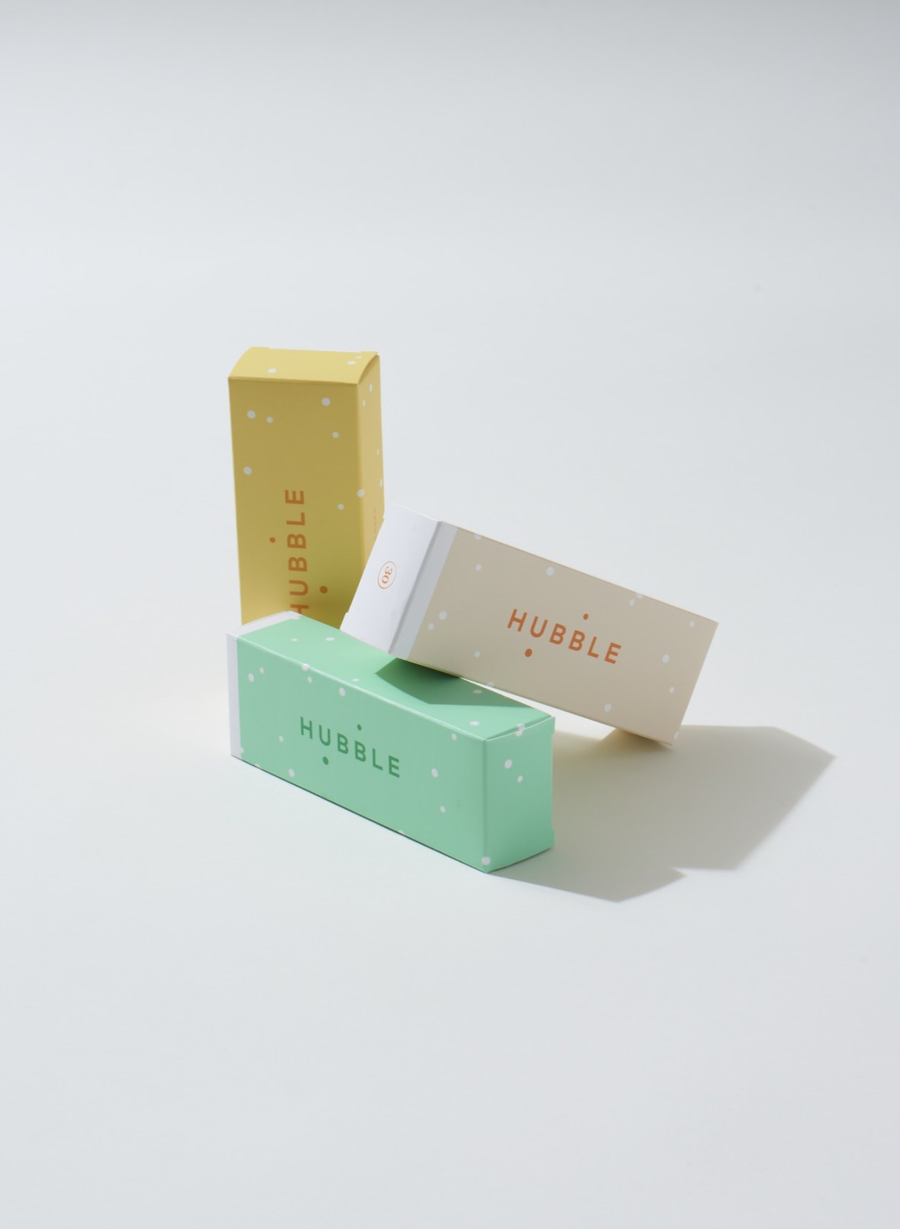 Hubble contact lens subscription boxes in yellow, mint green and beige packaging with polka dot design.
